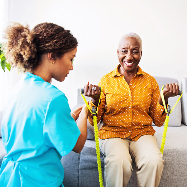 caretaker helping elderly woman with exercises